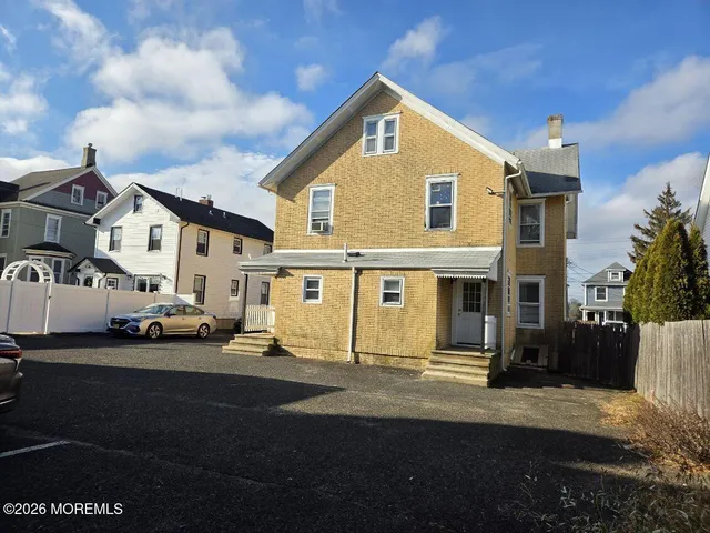 a view of a white house that has a car parked front of it