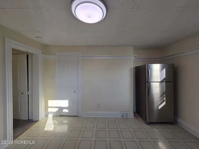 a view of a refrigerator in kitchen and an empty room