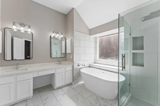 a bathroom with a bathtub a double vanity sink and mirror