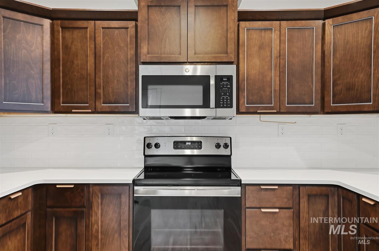 449 West Winnipeg Street Meridian, ID 83642 - Photo 12 of 49 Kitchen with stainless steel appliances, dark brown cabinetry, backsplash, and light stone counters