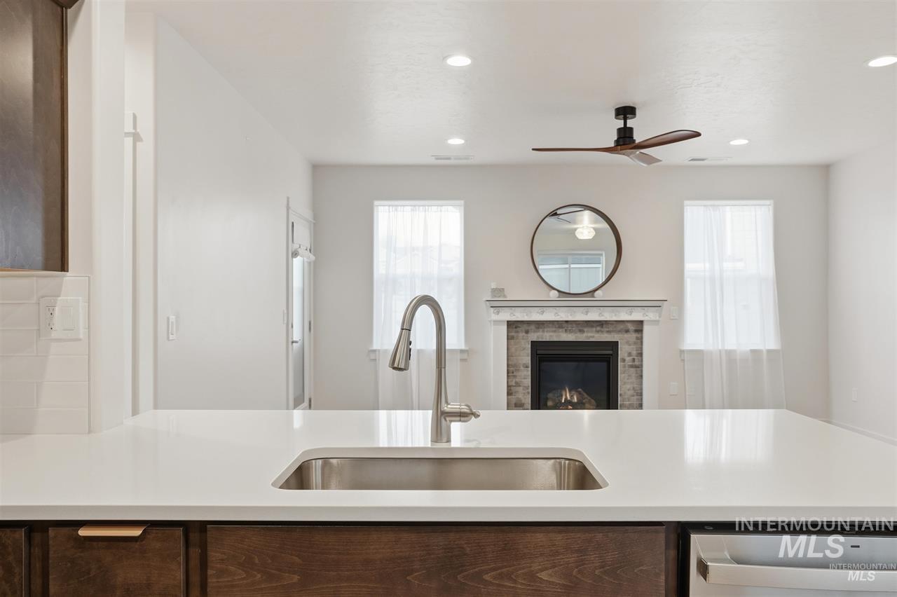 449 West Winnipeg Street Meridian, ID 83642 - Photo 13 of 49 Kitchen with dark brown cabinets, a ceiling fan, a brick fireplace, stainless steel dishwasher, and recessed lighting