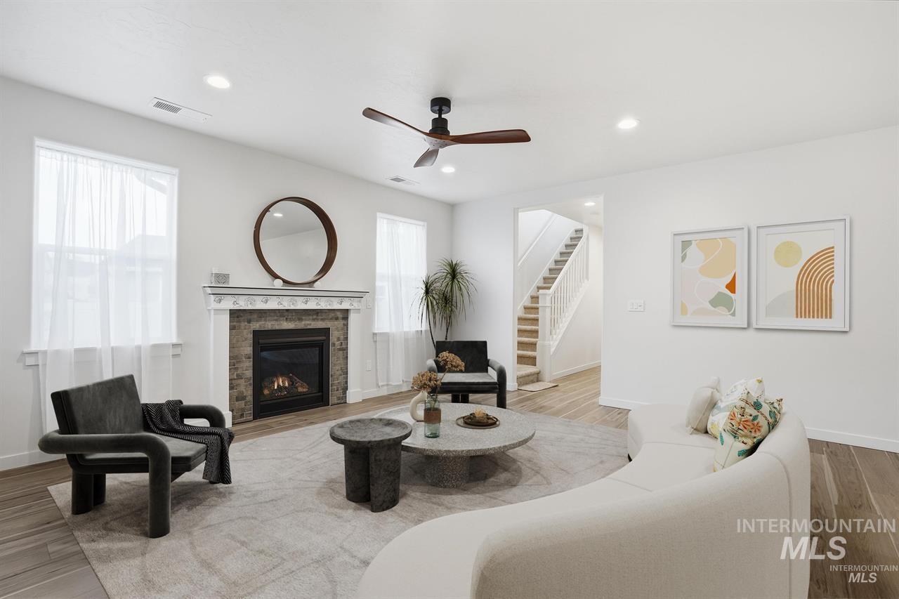 449 West Winnipeg Street Meridian, ID 83642 - Photo 7 of 49 Living room featuring wood finished floors, a ceiling fan, a glass covered fireplace, recessed lighting, and stairs