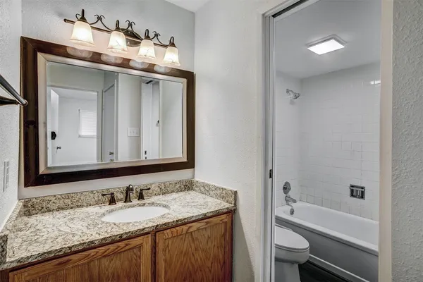 a bathroom with a granite countertop sink a toilet and bathtub