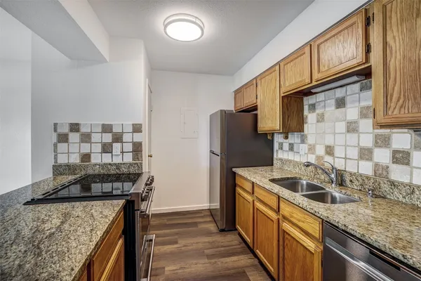 a kitchen that has a sink wooden cabinets and stainless steel appliances