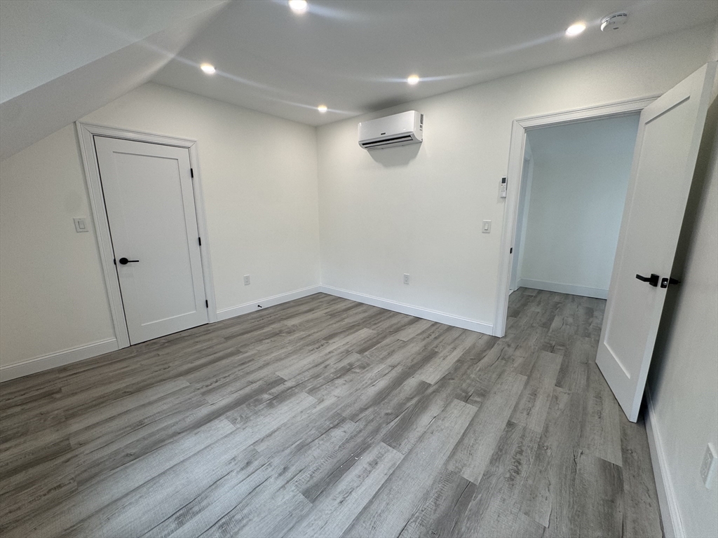 16 Adams Street, Unit 1 Boston, MA 02136 - Photo 12 of 15 an empty room with wooden floor and mirror