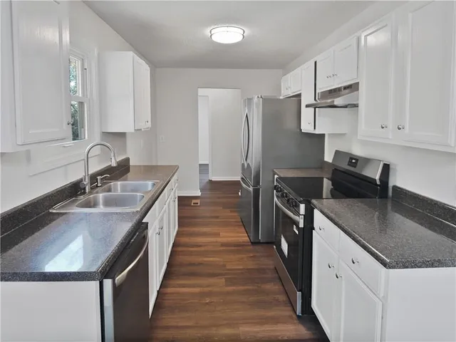 a kitchen with granite countertop a sink stove and refrigerator