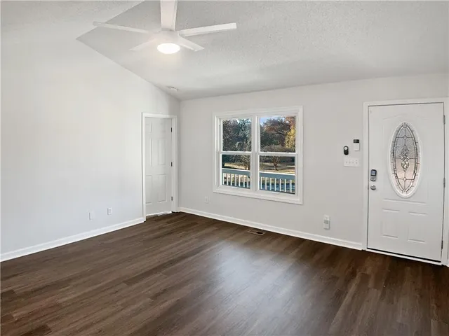 an empty room with wooden floor cabinet and windows