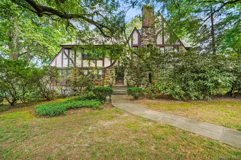 a pathway of a house with a yard and large trees