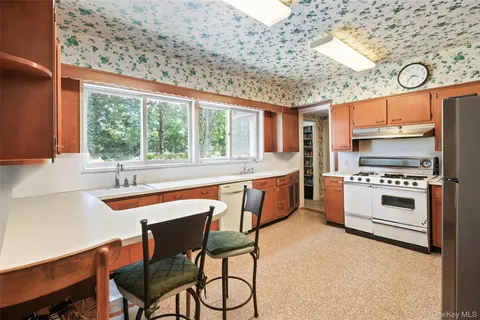 a kitchen with stainless steel appliances kitchen island a table chairs in it and wooden floors