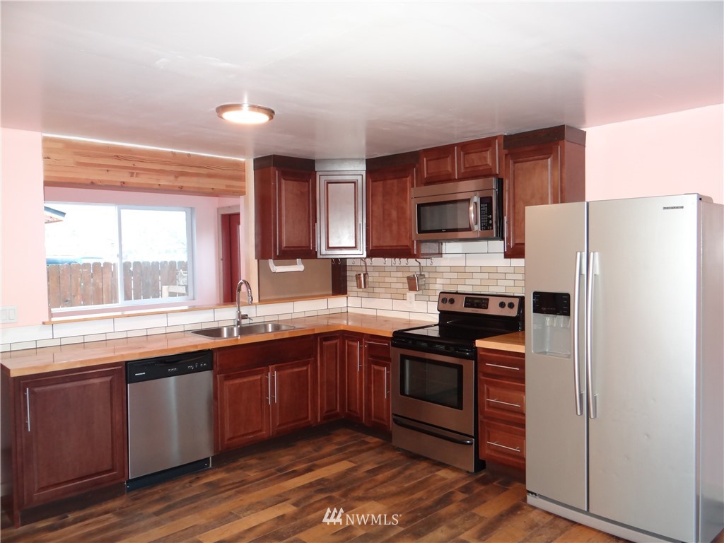 1306 Riverside Avenue Twisp, WA 98856 - Photo 8 of 22 a kitchen with stainless steel appliances granite countertop a refrigerator a sink dishwasher a stove with wooden cabinets and floor