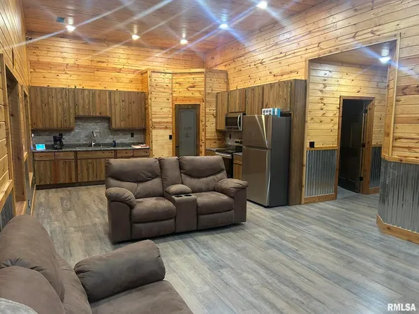 a living room with stainless steel appliances furniture a refrigerator and kitchen view