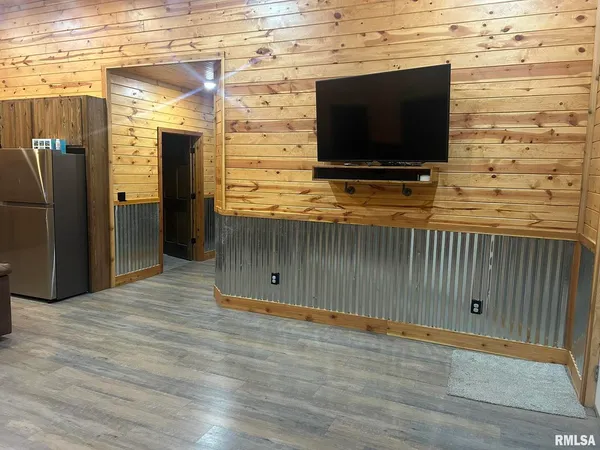 a view of empty room with wooden floor and tv