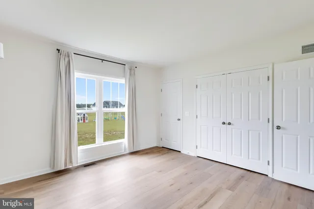 a view of an empty room with wooden floor and entryway