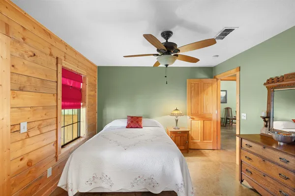 a bedroom with a bed a dresser next to a window