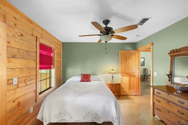 a bedroom with a bed a dresser next to a window