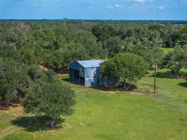 an aerial view of a house with a yard and trees all around