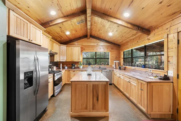 a large kitchen with kitchen island a large window a sink and stainless steel appliances