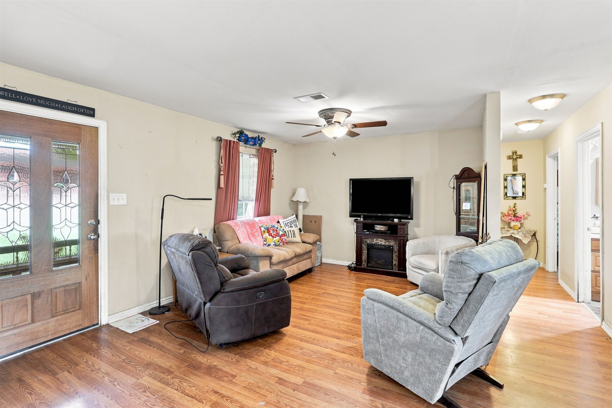 208 West Umstead Colbert, OK 74733 - Photo 6 of 25 Wood-finish flooring throughout, ceiling fan with integrated lighting, and a built-in media console with electric fireplace