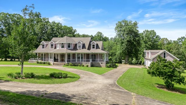 a front view of a house with a garden and trees
