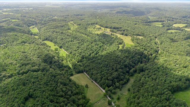 an aerial view of residential houses with outdoor space and trees