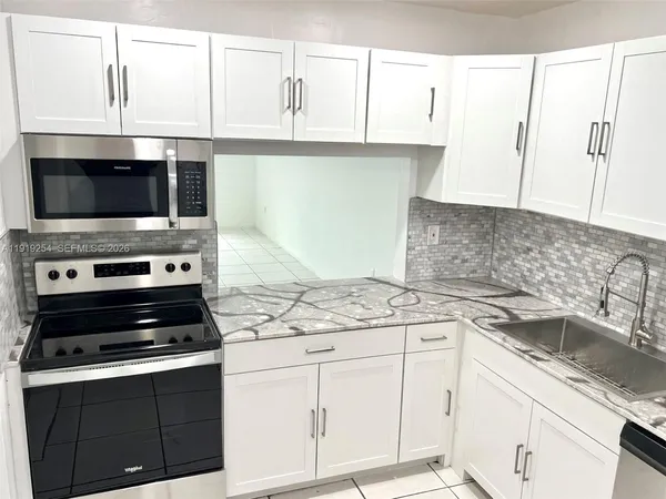 a kitchen with granite countertop a sink stove and microwave