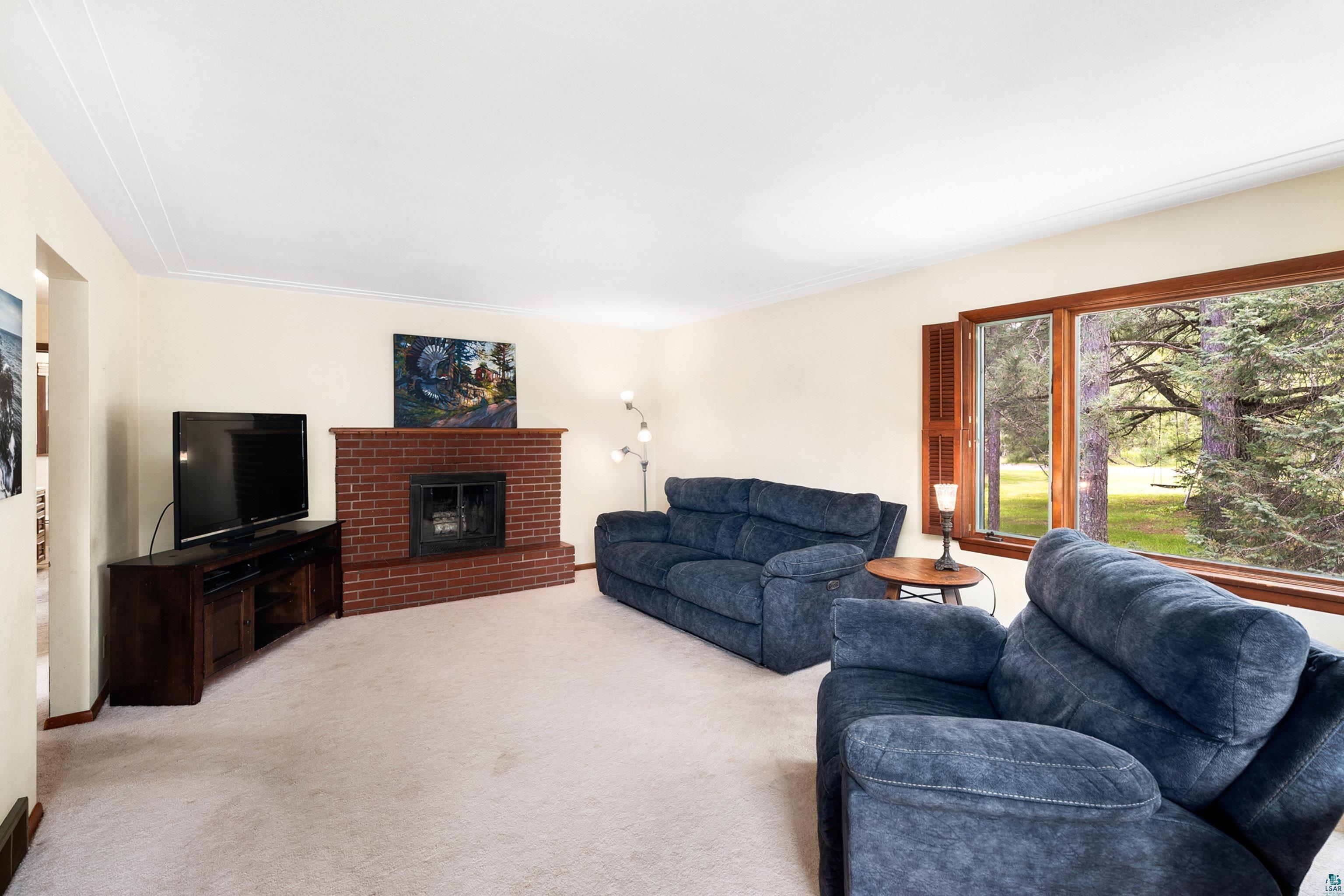 4808 Midway Road Duluth, MN 55811 - Photo 18 of 57 Living area featuring a brick fireplace with a black insert and a large window with wood trim