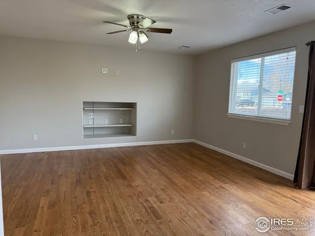 a view of an empty room with a window and wooden floor