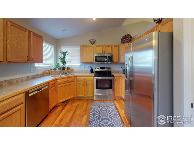 a kitchen with stainless steel appliances kitchen island granite countertop a refrigerator and a sink