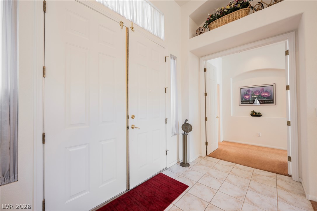 5494 Pine Ranch Street Las Vegas, NV 89113 - Photo 17 of 54 A welcoming entryway features dual white panel doors, a transom window, and warm tiled flooring.