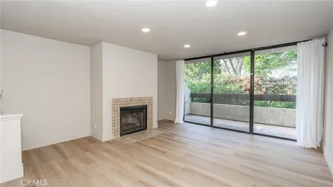 a view of an empty room with wooden floor and a fireplace