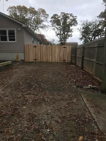 a view of a backyard with large trees and wooden fence