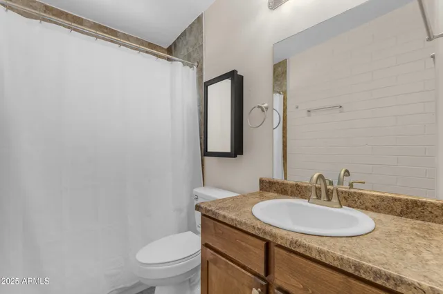 a bathroom with a granite countertop sink toilet and a mirror