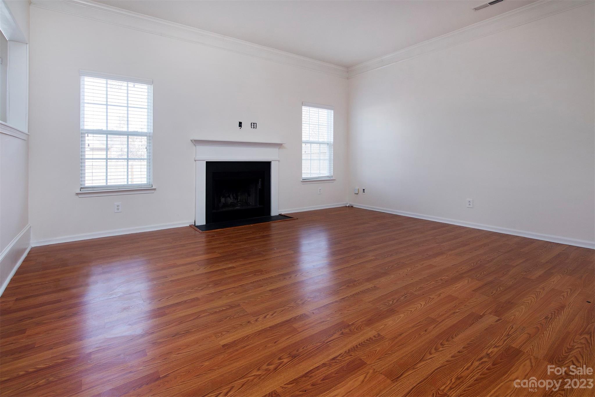 9629 Rothman Lane Charlotte, NC 28215 - Photo 4 of 24 an empty room with wooden floor fireplace and windows