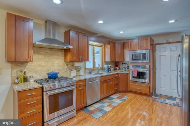 a kitchen with stainless steel appliances granite countertop wooden cabinets a sink and a window