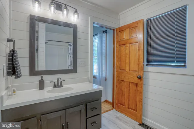 a spacious bathroom with a granite countertop sink a mirror and shower