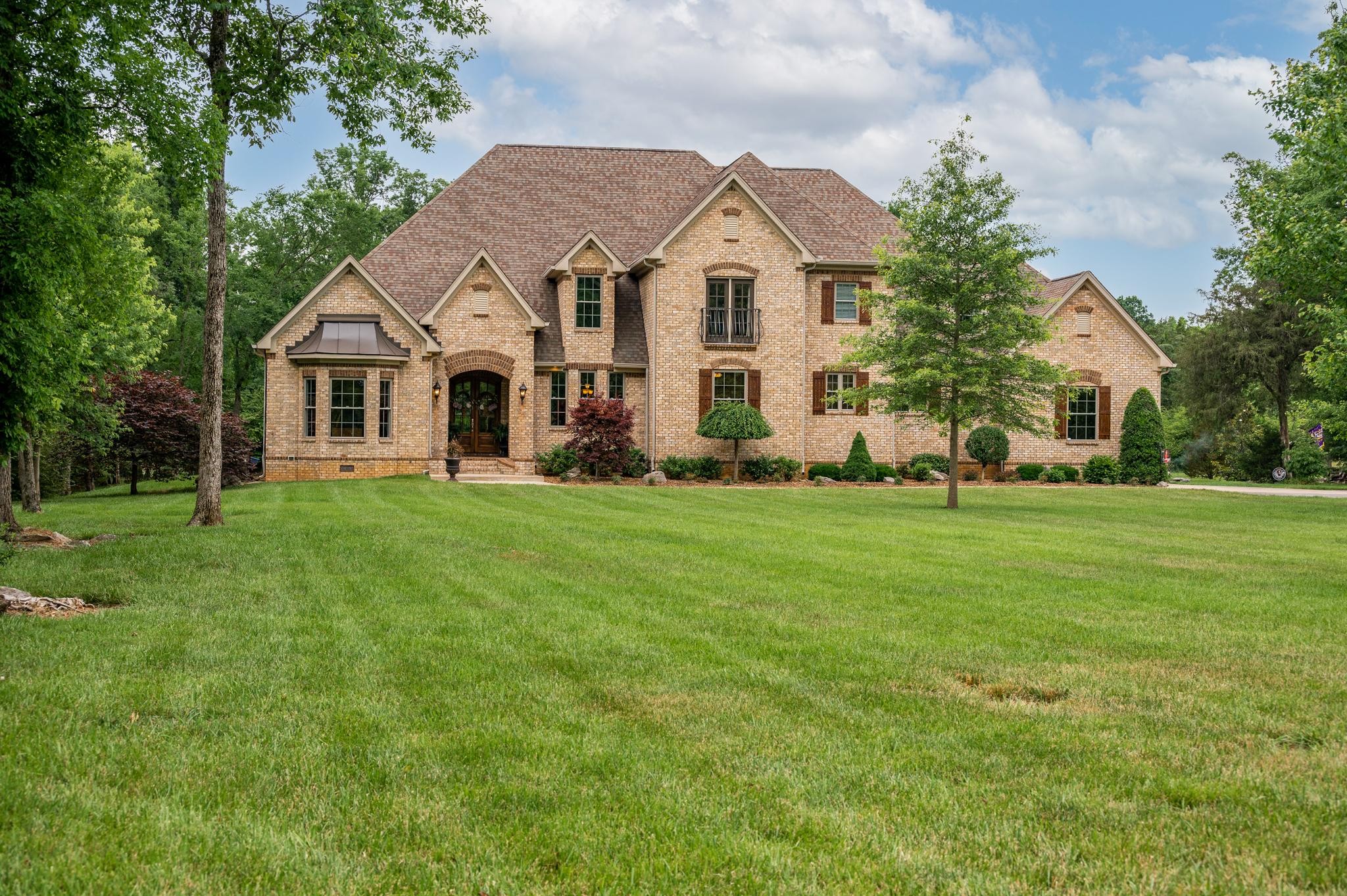 a front view of a house with a garden and trees