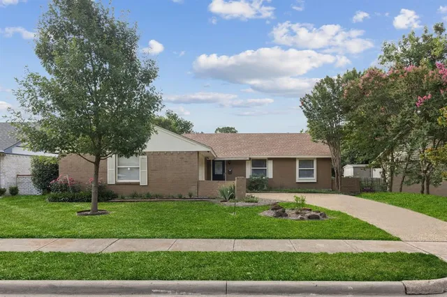 a front view of a house with a garden and trees