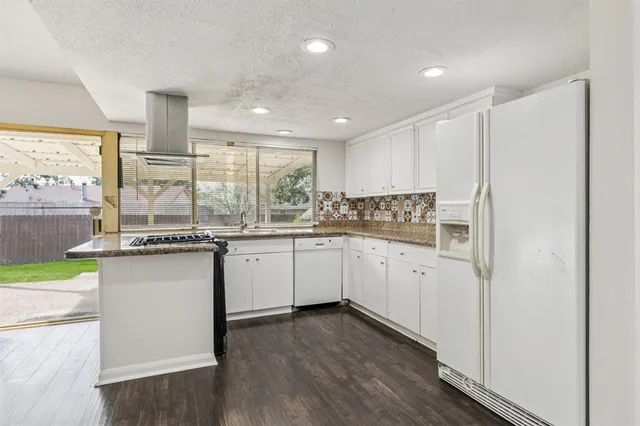 a kitchen with granite countertop white cabinets and white appliances