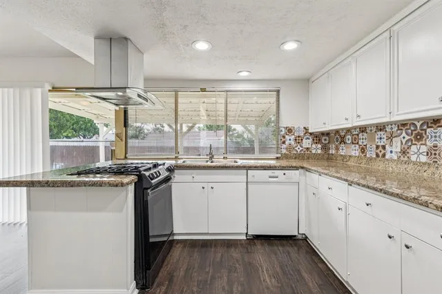a kitchen with granite countertop white cabinets and white appliances with wooden floor