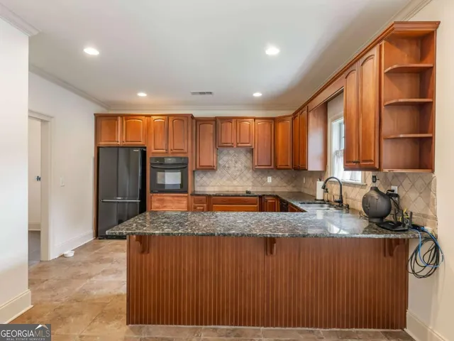 a kitchen with stainless steel appliances granite countertop wooden cabinets a refrigerator and a sink