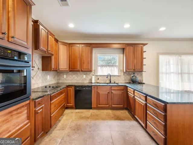 a large kitchen with stainless steel appliances granite countertop a stove top oven a sink dishwasher a dining table and chairs with wooden cabinets