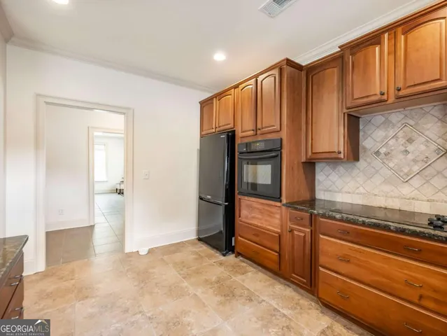 a view of kitchen with granite countertop cabinets and refrigerator
