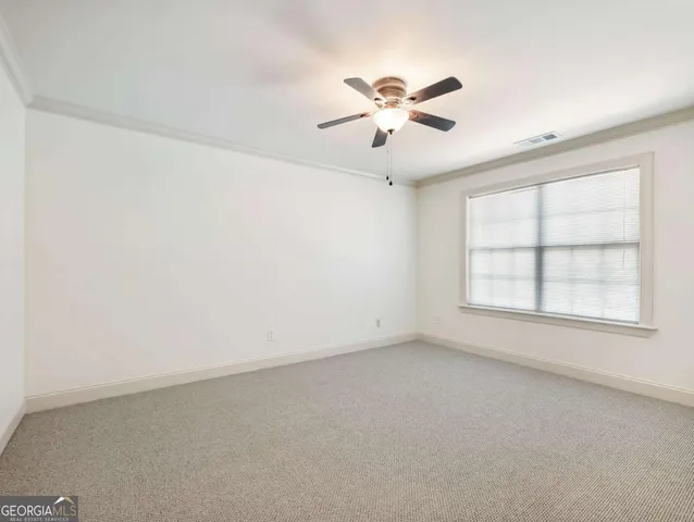an empty room with windows and fan