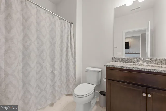 a bathroom with a granite countertop toilet and a sink