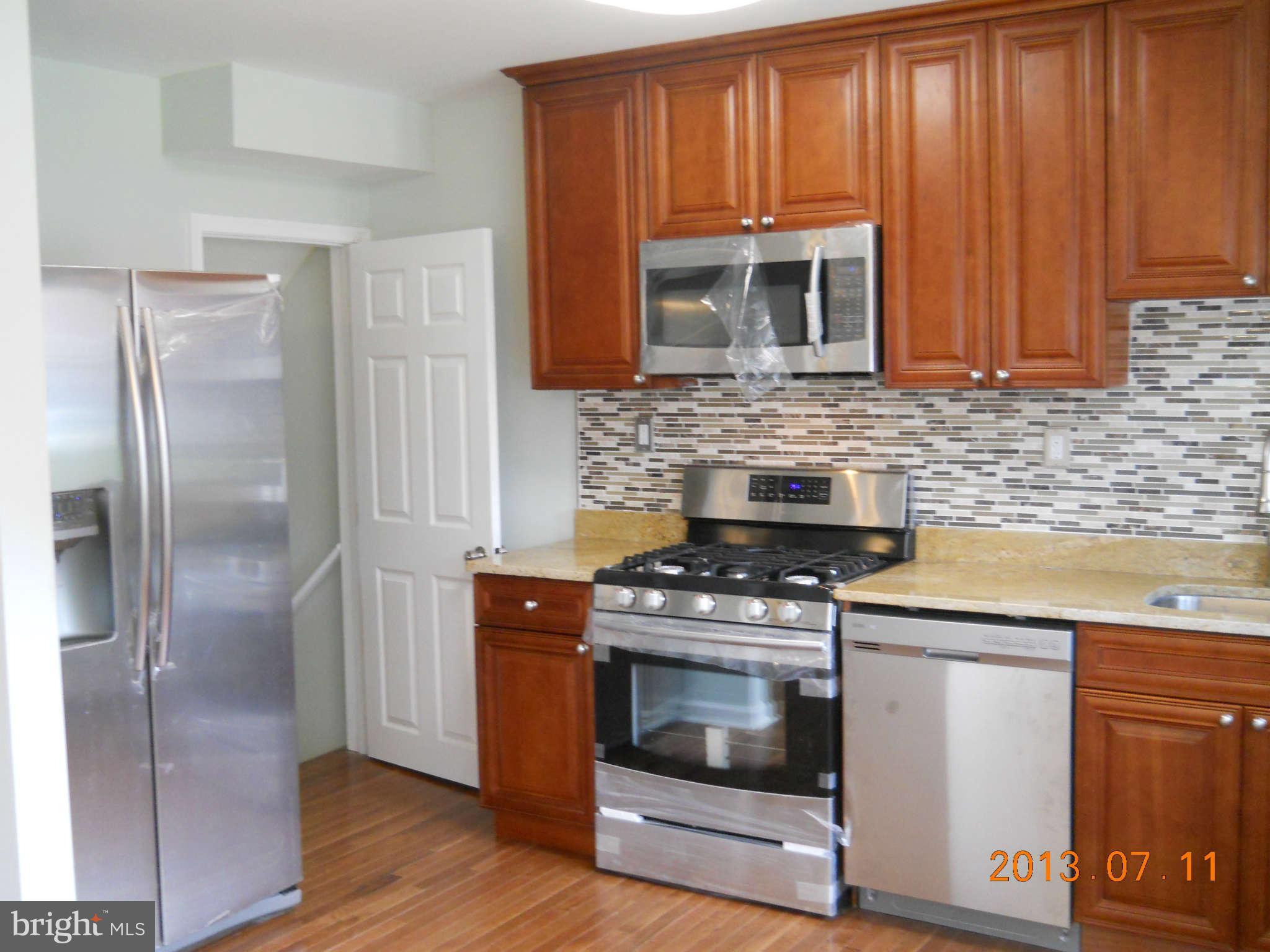 500 Queensgate Road Baltimore, MD 21229 - Photo 8 of 14 a kitchen with stainless steel appliances wooden cabinets and a stove top oven