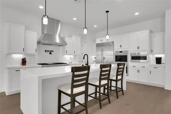 a kitchen with stainless steel appliances kitchen island a table chairs and a refrigerator