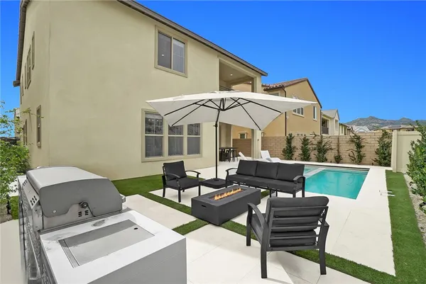 a view of a patio with couches table and chairs under an umbrella