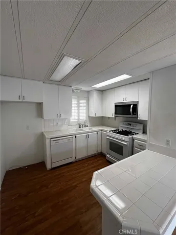 a kitchen with stainless steel appliances a sink a stove top oven a counter space and cabinets