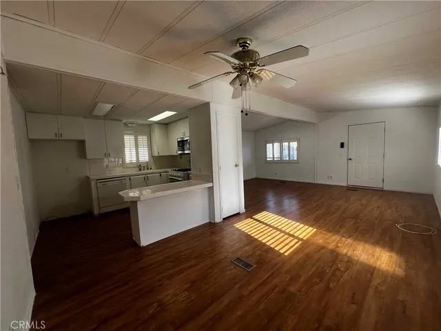 a view of kitchen and empty room with wooden floor