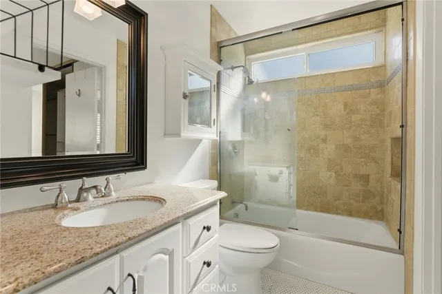 a bathroom with a granite countertop sink toilet and shower